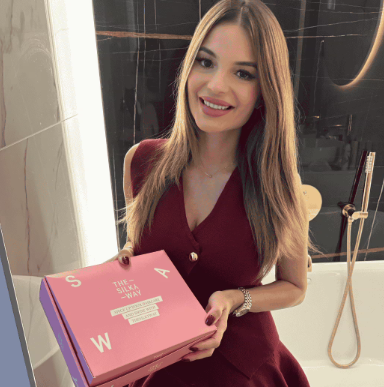 Vásárló mosolyogva tartja a TheSilkyWay hajregeneráló csomagot rózsaszín dobozban